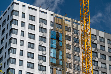 Construction of a modern residential building with a striking facade under a clear blue sky © beholdereye