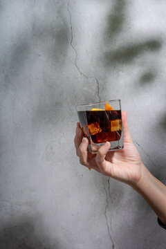 Hand holding a glass of vermouth on a concrete background