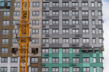 Colorful modern building under construction with a yellow crane capturing attention in a vibrant urban landscape © beholdereye
