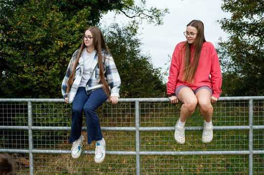 Teenager sisters sitting on a fence in Ireland