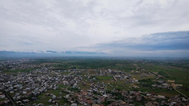 Drone ascending into cloudy sky revealing aerial landscape of Faisal Town near Srinagar Highway and Fateh Jang Road