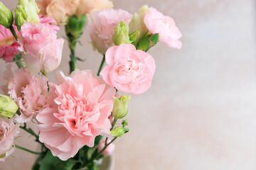 Fototapeta premium Pink flowers in a simple vase placed on a light background during daylight