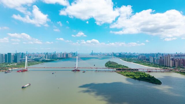 Aerial view of a modern bridge spanning across the wide river in the urban landscape of Wuhan China under a bright blue sky