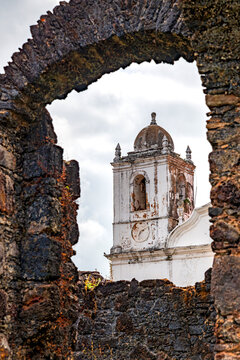 Baroque church tower seen through the stone ruins of the town of Alcantara in Maranhao.