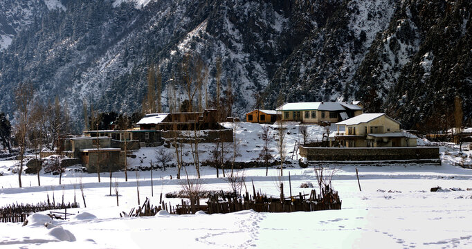 View of the snow-covered landscape of Kalam valley in Swat with traditional houses and rugged mountain slopes in winter, Kalam, Khyber Pakhtunkhwa, Pakistan.