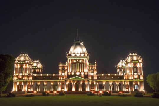 View of the illuminated Noor Mahal palace at night, featuring its grand domes and intricate architectural details set against a dark sky in Bahawalpur, Punjab, Pakistan.