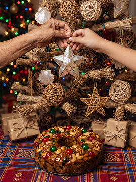 Hands Decorating Native Filipino Christmas Tree with Capiz Shell Ornament and Fruitcake
