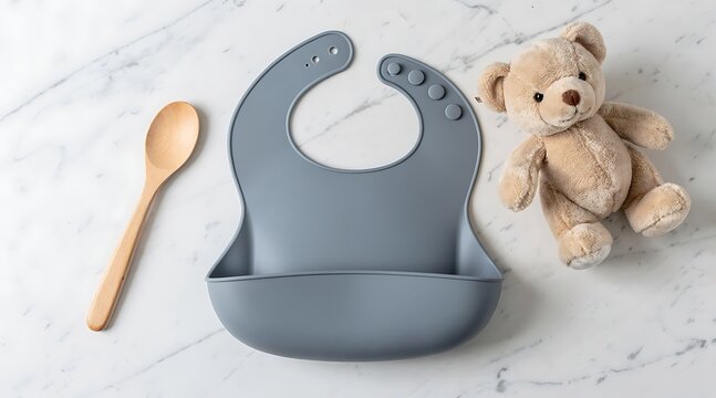 Grey silicone baby bib with wooden spoon and teddy bear.