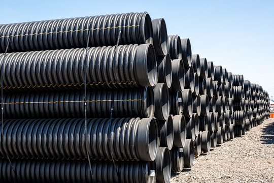 View of stacked black corrugated plastic pipes in an industrial storage yard in Eugene, Oregon, United States.