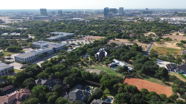 Private residential properties with tennis courts border corporate offices in North Texas region. Dense tree cover frames suburban estates across dynamic landscape of Frisco, Texas