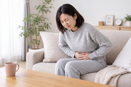 生理痛でお腹を押さえてつらそうにする女性