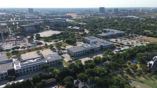 Sprawling office complexes border wooded grounds near Dallas North Tollway across Greater Dallas area. Paved transit lots adjoin vibrant campuses beside active foundation work, Frisco, Texas
