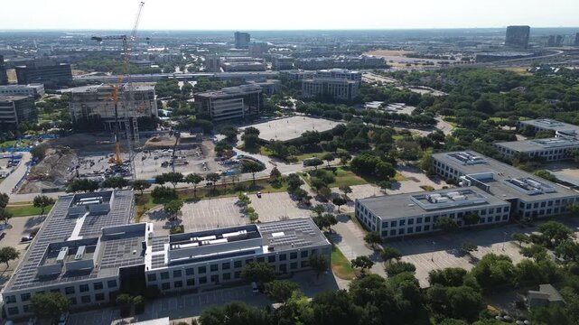 Heavy excavation machinery prepares building parcels beside Warren Parkway along Platinum Corridor. Tall lattice cranes assemble foundations near solar paneled offices, Frisco, Texas