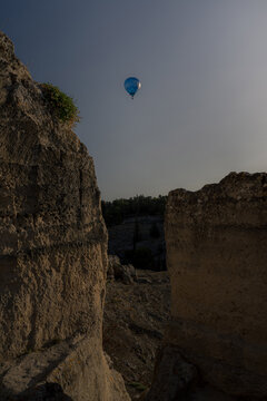 View of a hot air balloon floating above the rocky ravine landscape of Gravina in Puglia, Apulia, Italy.