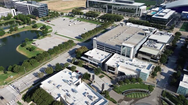 Tiered parking garage flanks multi building retail plaza near Dallas Parkway in North Texas region. Aerated retention basin borders paved roadways across evolving community in Frisco, Texas