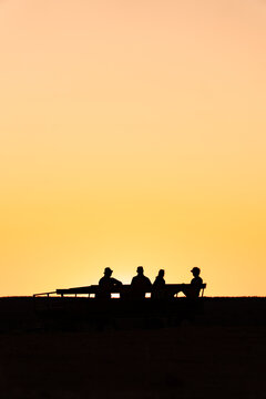 View of tourists silhouetted against a vibrant sunset sky while sitting on a wagon in the outback of Northern Territory, Australia.