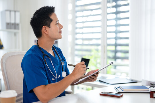 Happy male asian doctor, looks away with smile. Attractive successful man therapist  feel satisfied with career, healthcare mission.