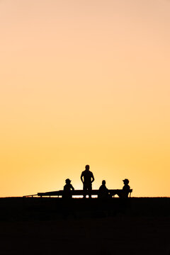 View of silhouettes of tourists standing on a vehicle in the outback against a vibrant sunset in Northern Territory, Australia.