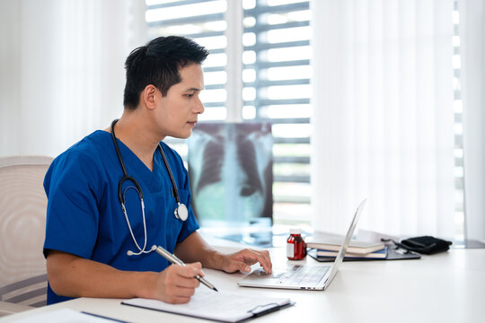 Doctor looking at laptop screen writing in notebook for research planning or medical tech innovation in hospital office. Healthcare medic worker, research strategy book notes and online communication.