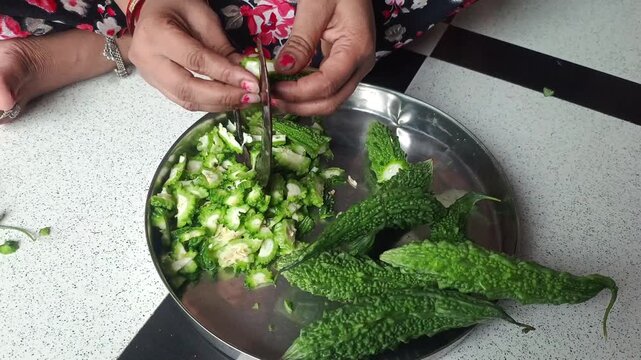Woman Cutting Fresh Bitter Gourd (Karela) with Traditional Indian Vegetable Cutter (Boti)
