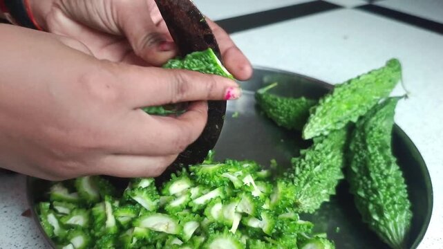 Woman Cutting Fresh Bitter Gourd (Karela) with Traditional Indian Vegetable Cutter (Boti)