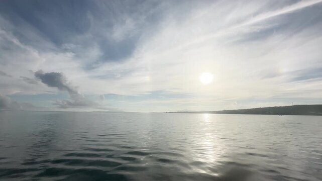 Horizontal seascape with sun halo phenomenon over calm ocean and blue sky, 4K