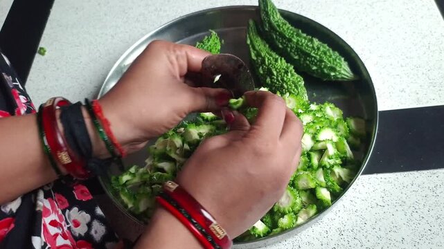 Woman Cutting Fresh Bitter Gourd (Karela) with Traditional Indian Vegetable Cutter (Boti)