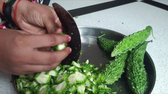 Woman Cutting Fresh Bitter Gourd (Karela) with Traditional Indian Vegetable Cutter (Boti)