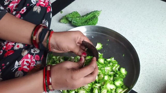 Woman Cutting Fresh Bitter Gourd (Karela) with Traditional Indian Vegetable Cutter (Boti)
