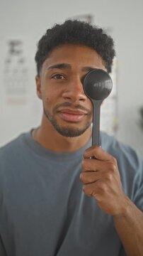 Man holding occluder over one eye during an optometry clinic exam, hand visible and facing an eye chart; calm care.