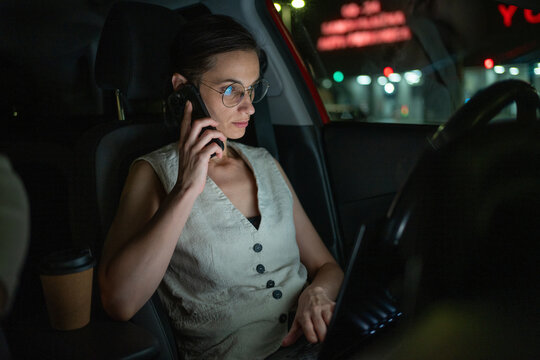 Businesswoman talking on phone and working late hours from a car