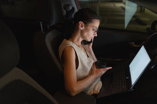 Businesswoman working late hours from a parked car
