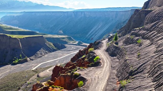 Aerial view of a winding dirt road on a steep cliff of the colorful eroded canyon in Anjihai Grand Canyon, Xinjiang, China