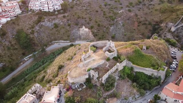 Epic aerial pullback from ancient Norman Castle ruins revealing the scenic coastal town of Scalea, terracotta roofs, and Mediterranean sea, Calabria, Italy, 1080p.