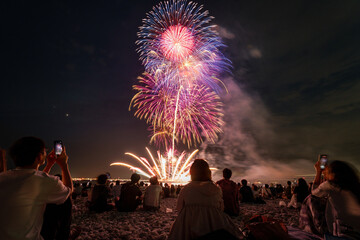 Fototapeta premium Grand fireworks finale above a beach crowd in Osaka Japan