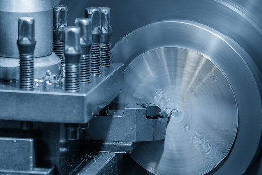 Close up of a lathe machine face cutting a metal part in a blue tone scene