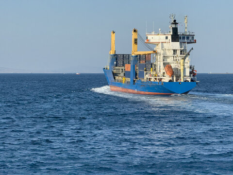 View of a blue cargo ship carrying containers across the deep blue sea under a clear sky in Canakkale Merkez, Canakkale, Turkey.