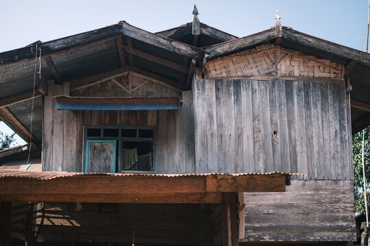 View of a traditional wooden house of a Hmong tribe featuring weathered timber walls and a corrugated metal roof in Laos.