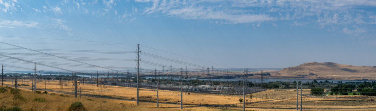 View of McNary Lock Dam and the electrical substation with power lines stretching across the dry landscape near the Columbia River in Umatilla, Oregon, United States.