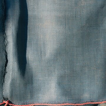 Wet woven polypropylene sandbag surface with a damp texture and coral twine, featuring heavy utility fibers for flood defence and disaster risk reduction