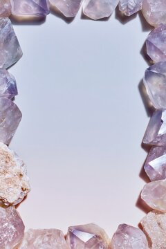 Raw amethyst chunks forming a luminous border on a pale lilac background with copy space for wellness and jewelry branding