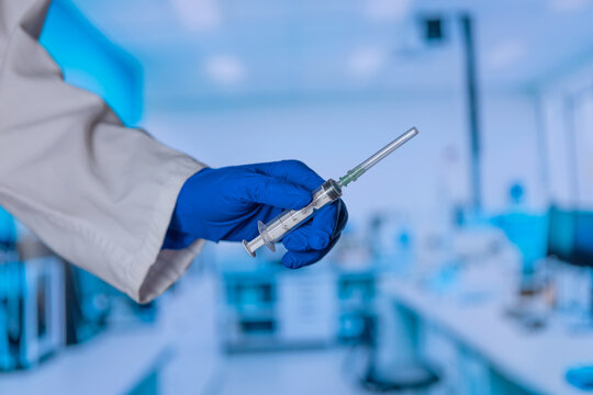 Blue-gloved hand holds surgical needle. Lab background shows blurred equipment. Clean clinical setting emphasizes precision. Ideal for medical research or surgical training