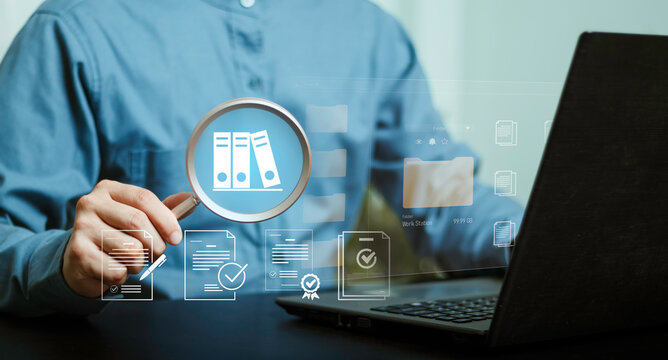 Digital document management concept, magnifying glass reviewing files and folders beside a laptop. Document search, records management, administration, organization, compliance and workflow.