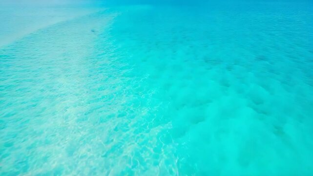 Aerial view of crystal clear turquoise ocean water with sandy seabed patterns