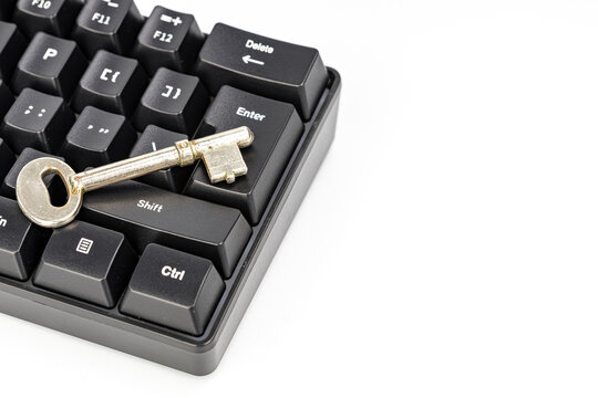 Close-up of a rustic vintage skeleton key resting on the enter key of a modern black mechanical keyboard, symbolizing the concept of digital security, password protection, and access control