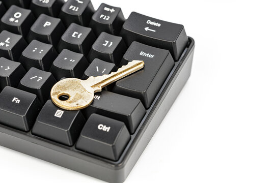 Close-up shot of a gold house key placed on the enter key of a black mechanical computer keyboard, symbolizing online security, data protection, and digital access control