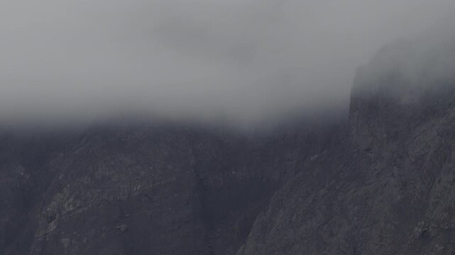 Low cloud layer on rocky cliffs at mountain peak