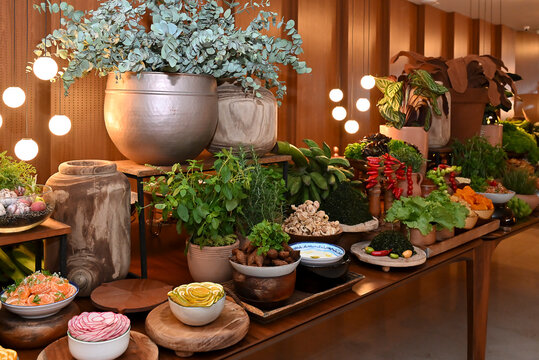 brazilian feijoada side dishes with couve, torresmo, red pimenta dedo de mo&ccedil;a, potted herbs, green bananas, and white sauce, catering buffet table setup horizontal shot
