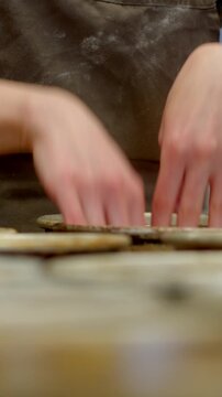 close-up vertical motion of baker hands carefully placing and adjusting round dough pieces on multiple metal trays, both hands hover and touch tray rims while hand