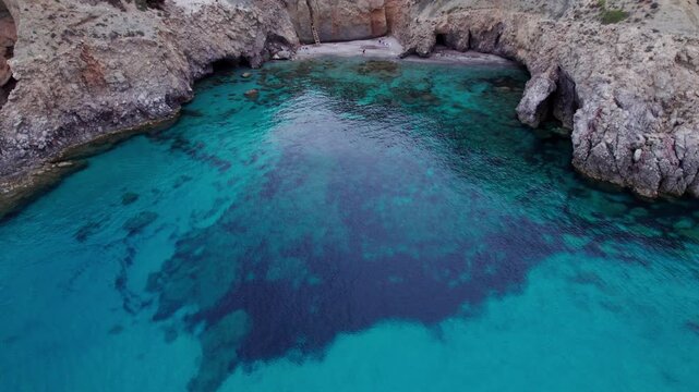 Reveal of Secluded Greek beach at Tsigrado, accessible only by ladder and rope. Turquoise water and massive cliffs on Milos Island. Perfect for adventure stock footage